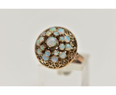 A YELLOW METAL OPAL RING, tiered ring set with nineteen opal cabochons, to the openwork scroll surround, polished band, unmar