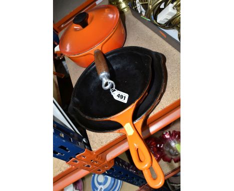THREE LE CREUSET PANS, in orange, comprising a covered saucepan with pouring spout, diameter 20cm, and two frying pans with t