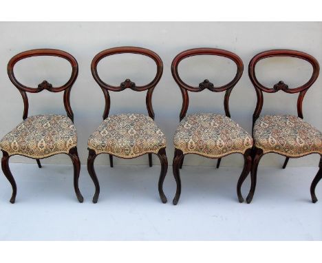 A set of four Victorian spoon-back mahogany dining chairs with carved supports, fabric upholstered seats on cabriole legs in 