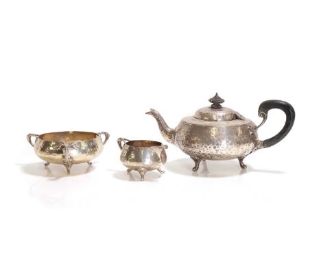 A silver three-piece tea set, by Charles Edwards, London 1916,each piece hammered, with scrolled supports and handles, teapot