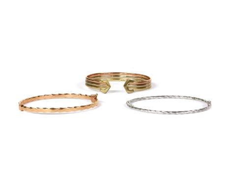 A 9ct three colour gold torque bangle, rose, white and yellow gold sections with arrow shaped terminals, Sheffield, internal 