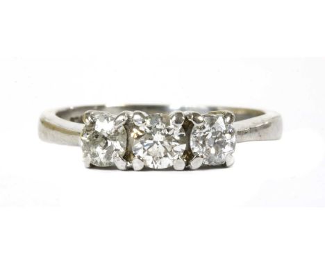 A 9ct white gold three stone diamond ring, a brilliant cut diamond with a smaller old European cut diamond at each side, all 