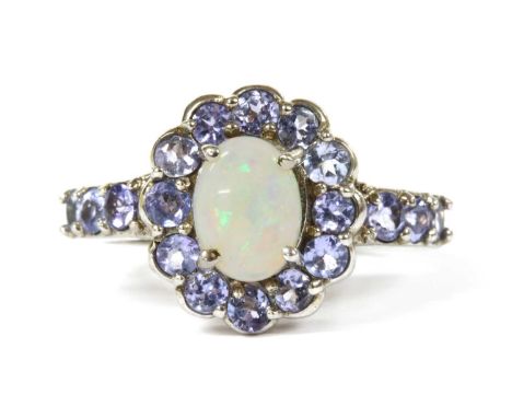 A 9ct white gold opal and tanzanite cluster ring, an oval cabochon opal, approximately 8 x 6mm, claw set to surround of circu