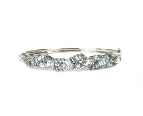A white gold aquamarine oval hinged bangle, three diagonal rows of graduated baguette cut aquamarines, with pear and oval mix