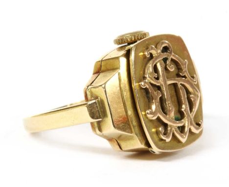 A gold mechanical watch ring, the watch with hinged cover with applied monogram, possibly 'SL', to silvered dial, black Arabi