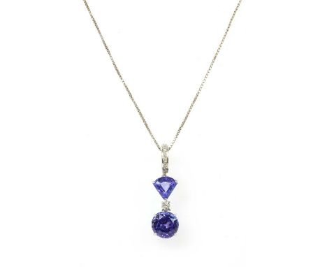 A white gold tanzanite and diamond pendant, a circular mixed cut tanzanite, approximately 9mm diameter, surmounted with a bri