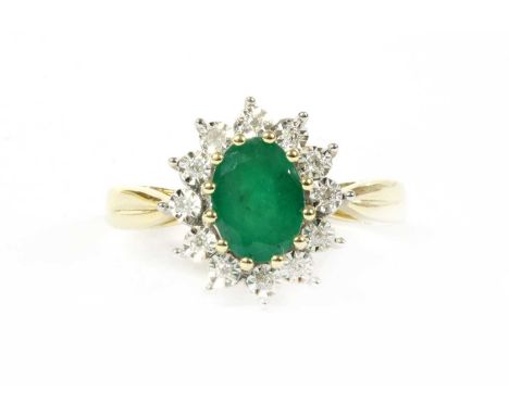 A gold emerald and diamond cluster ring, an oval mixed cut emerald, claw set to surround of brilliant cut diamonds grain set 