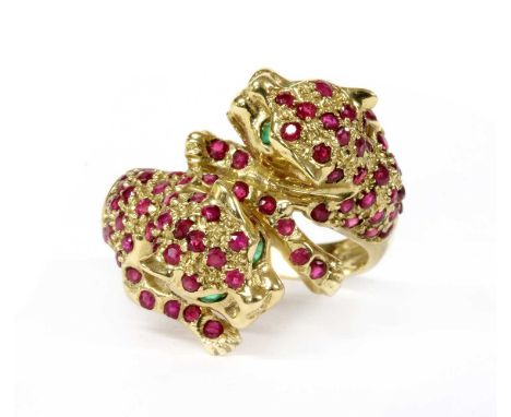 A 9ct gold ruby and emerald set panther ring, the crossover head designed as two opposing panthers, grain set throughout with