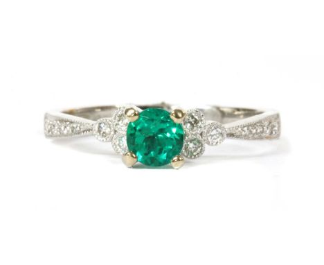 An 18ct white gold emerald and diamond ring, a circular mixed cut emerald, with a stated weight of 0.35ct, claw set, with a t