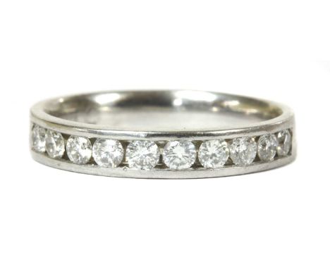 A white gold diamond half eternity ring, a row of brilliant cut diamonds, channel set to a flat court section shank, tested a