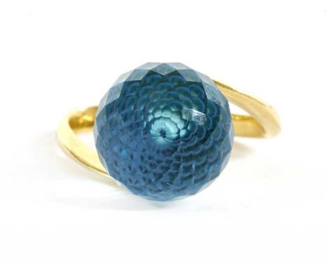 A Russian gold blue topaz ring, a spherical chequerboard cut blue topaz, peg set, to crossover shoulders and a plain shank, m