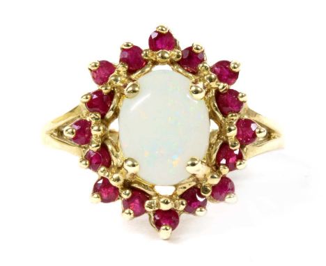 A 9ct gold opal and ruby cluster ring, an oval cabochon opal, claw set to surround of circular mixed cut rubies, with split s