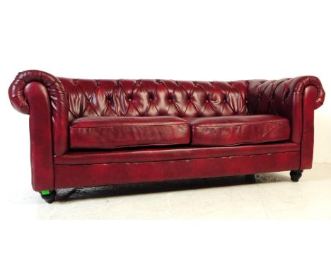 A red oxblood chesterfield three seater sofa / settee. Having a button back back rest with scrolled elbow rests in the same s