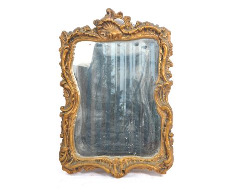 A vintage reproduction gilt plaster Florentine wall mirror. Central mirror glass within a rococo scroll worked composite gilt