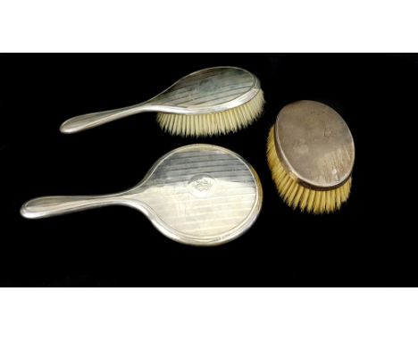 A silver backed hand mirror, striped engine turned decoration; a conforming hairbrush and one other brush, various dates and 