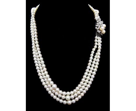 A three strand graduated cultured pearl necklace with diamond and pearl clasp of three pearls set in a spray of foliage in wh