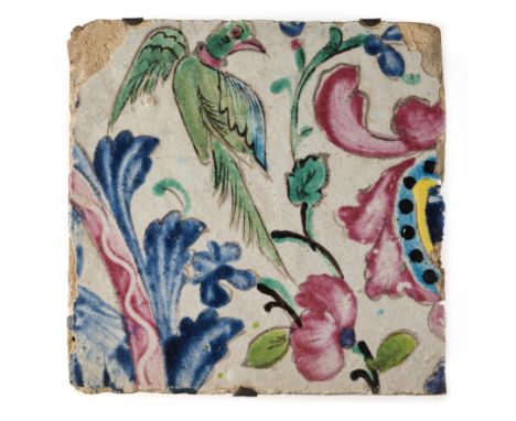 A QAJAR CUERDA SECA TILE, PERSIA, 19TH CENTURY polychrome glazed buff earthenware, depicting a green parakeet amidst floral a