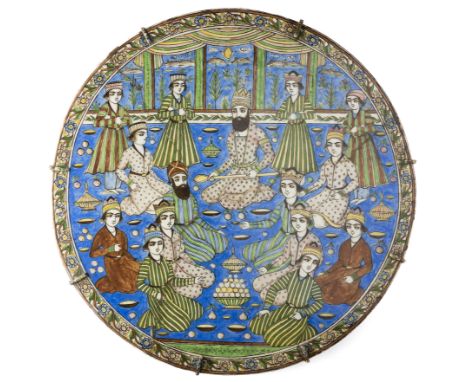 A LARGE QAJAR CIRCULAR TILE, PERSIA, CIRCA 1880-1890 underglaze painted fritware, depicting a ruler and his courtiers feastin