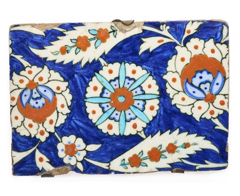 AN IZNIK BORDER TILE FRAGMENT, OTTOMAN ANATOLIA, CIRCA 1580 underglaze painted fritware, with stylised flower and composite s