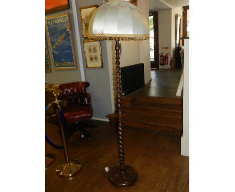A 1920's oak standard lamp, with a pleated silk shade, raised on a barley twist column support and circular spreading base. H