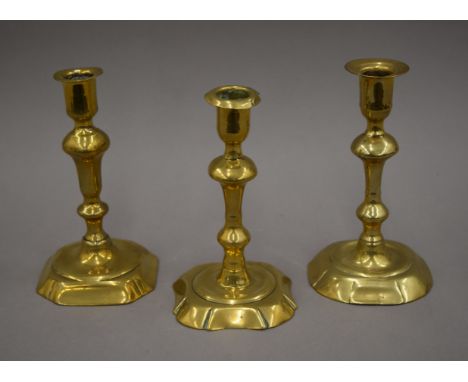 An 18th century brass candlestick on a canted corner base and two other brass candlesticks. The former 18 cm high.