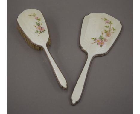 A silver and enamel dressing table brush and a mirror.