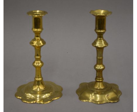 An 18th century brass candlestick with petal edge drip pan and base, and another similar on a scallop edge base. 19 cm high.