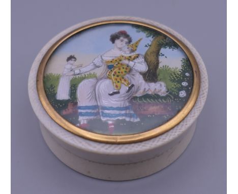 An 18th/19th century ivory patch box, the lid inset with a miniature portrait of a young girl playing with dolls. 5.5 cm diam