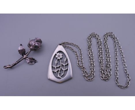 A silver brooch formed as a rose and a florally decorated pendant on chain. The former 5.25 cm high.