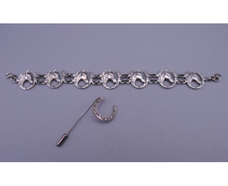 A silver horseshoe and horses head bracelet, and a horseshoe stick pin. The former 19 cm long.