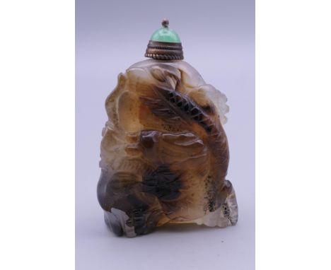 A carved mottled agate snuff bottle with large dragon to front with green jade stopper. 5.5 cm high.