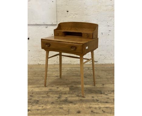 Ercol, an elm and beech writing desk, the superstructure with two drawers and open shelf, above a frieze drawer and raised on