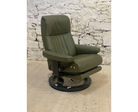 A Vintage Ekornes Stressless electric reclining lounge chair, upholstered in green leather and raised on a circular base. H10