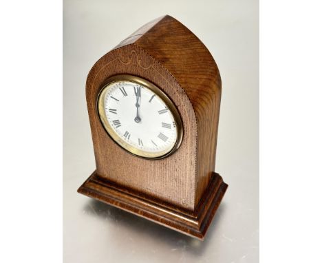 A Edwardian oak inlaid lancet mantle clock with brass mounted white enamel dial and roman numerals raised on stepped base and