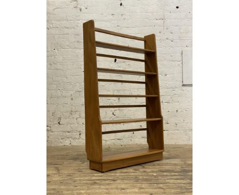 Ercol, an elm open bookcase shelf, with two fixed and two adjustable shelves on tapered panel end supports and an inset plint