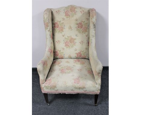 An Edwardian wingback armchair upholstered in a floral tapestry fabric 