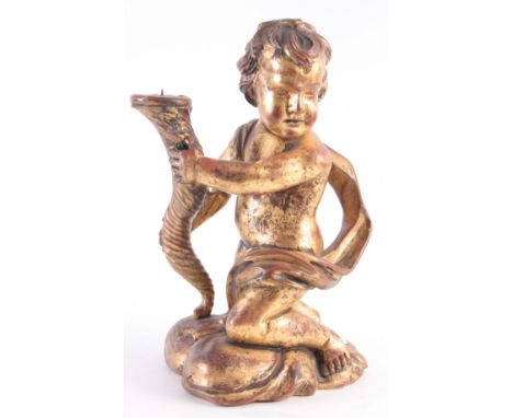 A LATE GEORGIAN GILTWOOD CARVED CHERUB CANDLESTICK, with traces of red ocher showing through the gilding 40cm by 25cm wide.