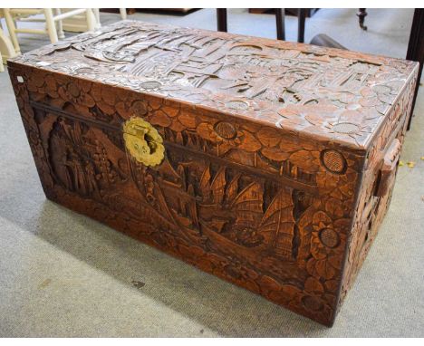 A 20th century carved camphor wood chest decorated with oriental figures in a landscape, 101cm by 50cm by 49cm