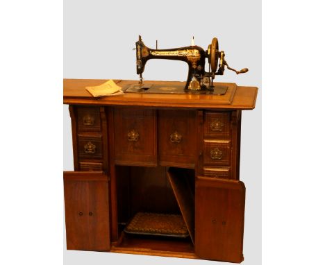 A Singer manual sewing machine (model R1019453), with gilt embossed and painted Egyptian iconography decoration, in a mahogan