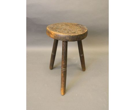 A C19th carved oak milking stool on turned spindle legs, 13½'' high 