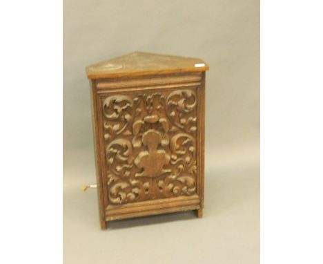 A standing oak corner cabinet with a decoratively carved door opening to reveal a loud speaker, 20'' x 30'' x 13'', Best Bid 