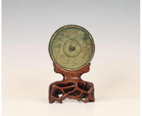 China, a bronze circular mirror, possibly Tang dynasty (618-907), cast with rings and raised central knob, on later wood stan