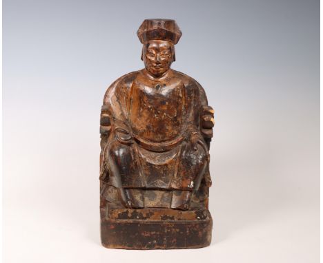 China, lacquered woorden model of a dignitary, 18th/ 19th century, shown seated on a horse-shoe backed chair, holding a table
