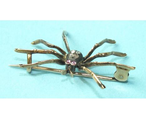 An Edwardian spider brooch with ruby eyes and body set with four rose-cut diamonds, unmarked, 38mm across, 3.6g.