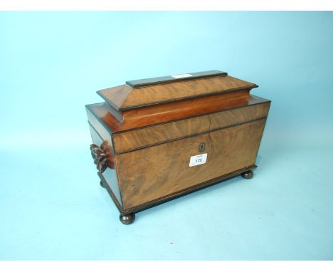 An early-19th century mahogany three-division tea caddy of sarcophagus shape, with shell-carved handles, on turned ebony ball