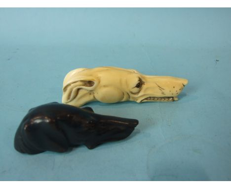 A carved ivory walking stick handle in the form of a dog with glass eyes, 11cm long and a similar carved ebony dog stick hand