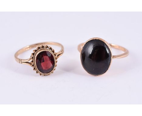 
	
		TWO GARNET RINGS 
		The first a late Victorian oval cabochon garnet within a closed back collet setting, unmarked; the s