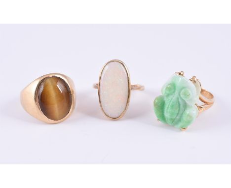 
	
		THREE GEM-SET DRESS RINGS
		The first set with a carved jadeite jade frog, claw set to a trifurcated hoop, stamped 14K; 