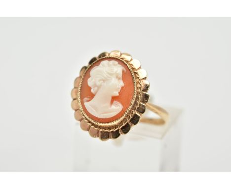 A YELLOW METAL CAMEO RING, the cameo of oval design depicting a lady in profile, within a collet mount, rope twist and scallo