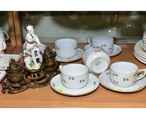 A BRONZED DOUBLE INK WELL, with blindfolded porcelain cherub to the centre, the ink wells in the form of cauldrons, on pierce